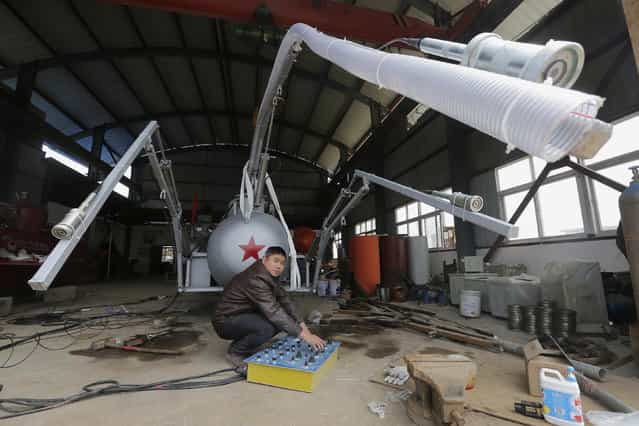 Zhang Wuyi looks up as he squats under a suction pipe of his new submarine that captures sea cucumbers at his workshop in Wuhan, Hubei province, March 25, 2013. Zhang, a 38-year-old local farmer who is interested in scientific inventions, has independently made eight miniature submarines with several fellow engineers, one of which was sold to a businessman in Dalian at a price of 100,000 yuan ($15,855) in 2011. The submarines, mainly designed for harvesting aquatic products, such as sea cucumber, have a diving depth of 20-30 metres (66-98 feet), and can travel for 10 hours, local media reported. (Photo by Reuters/Stringer)