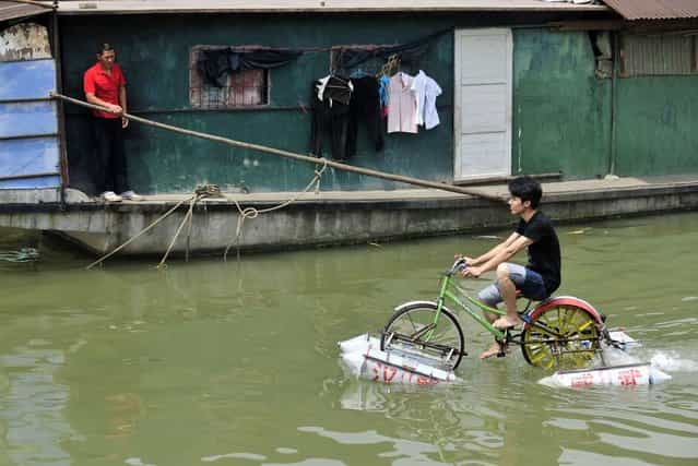 Lei Zhiqian rides a modified bicycle across the Hanjiang River, a tributary of the Yangtze River in Wuhan, Hubei province, China, June 16, 2010. The bicycle, equipped with eight empty water containers at the bottom, was modified by Lei's instructor Li Weiguo, who hopes to put his invention into the market. (Photo by Reuters/China Daily)