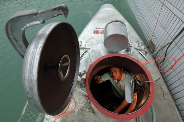 Zhang Wuyi sits in his double-seater submarine during a test operation at an artificial pool near a shipyard in Wuhan, Hubei province May 7, 2012. Zhang, a 37-year-old local farmer, who is interested in scientific inventions, has made six miniature submarines with several fellow engineers, one of which was sold to a businessman in Dalian at a price of 100,000 yuan ($15,855) last October. The submarines, mainly designed for harvesting aquatic products, such as sea cucumber, have a diving depth of 20-30 metres, and can travel for 10 hours, local media reported. Picture taken May 7, 2012. (Photo by Reuters/Stringer)