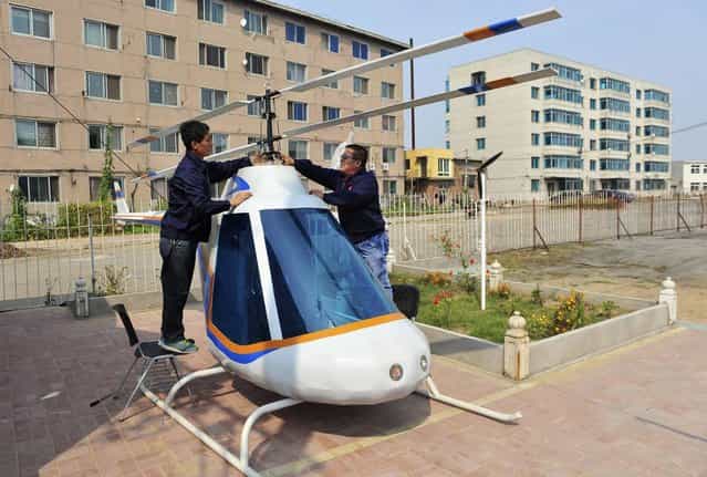 Tian Shengying (R), a 55-year-old blacksmith, adjusts the rotor of the helicopter, in Shenyang, Liaoning province, September 21, 2012. Tian built the bottom, body, tail and rotor of the helicopter single-handedly without a detailed blueprint in just half a month after receiving a request by an unmanned aircraft research centre. (Photo by Sheng Li/Reuters)