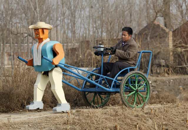 Farmer Wu Yulu drives his rickshaw pulled by a his self-made walking robot near his home in a village at the outskirts of Beijing January 8, 2009. This robot is the latest and largest development of hobby inventor Wu, who started to build robots in 1986, made of wire, metal, screws and nails found in rubbish sites. (Photo by Reinhard Krause/Reuters)