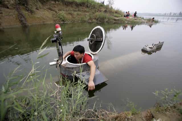 Tao Xiangli gets out of his homemade submarine after operating it in a lake on the outskirts of Beijing September 3, 2009. Amateur inventor Tao, 34, made a fully functional submarine, which has a periscope, depth control tanks, electric motors, manometer, and two propellers, from old oil barrels and tools which he bought at a second-hand market. He took 2 years to invent and test the submarine which costs 30,000 yuan ($4,385). (Photo by Christina Hu/Reuters)