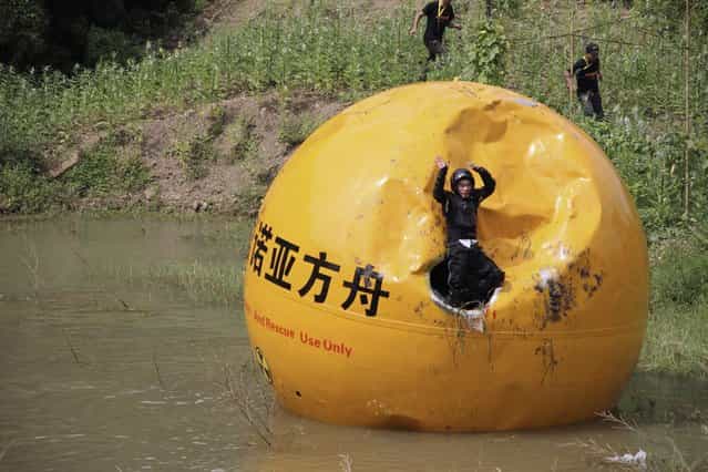A Chinese inventor, Yang Zongfu celebrates on his six-ton (5,443 kg) ball container named Noah's Ark of China after he succeeds in a series of tests of the vessel in Yiwu, Zhejiang province, August 6, 2012. According to local media, Yang spent two years and 1.5 million RMB (235,585 USD) to build this four-metre diameter vessel, which has been tested capable of housing a three-person family and sufficient food for them to live in 10 months. The vessel was designed to protect people inside from external heat, water and external impact. (Photo by Reuters/China Daily)
