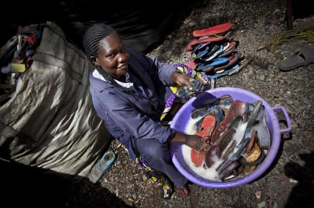 In this photo taken Monday, April 29, 2013, worker Jacqueline Achien washes discarded flip-flops in a bucket prior to them being sorted and carved into toy animals, at the Ocean Sole flip-flop recycling company in Nairobi, Kenya. The company is cleaning the East African country's beaches of used, washed-up flip-flops and the dirty pieces of rubber that were once cruising the Indian Ocean's currents are now being turned into colorful handmade giraffes, elephants and other toy animals. (Photo by Ben Curtis/AP Photo)