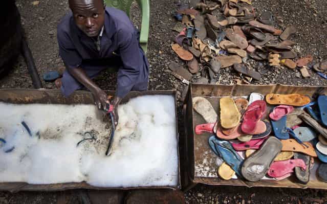 In this photo taken Monday, April 29, 2013, a worker washes and scrubs discarded flip-flops prior to them being sorted and carved into toy animals, at the Ocean Sole flip-flop recycling company in Nairobi, Kenya. The company is cleaning the East African country's beaches of used, washed-up flip-flops and the dirty pieces of rubber that were once cruising the Indian Ocean's currents are now being turned into colorful handmade giraffes, elephants and other toy animals. (Photo by Ben Curtis/AP Photo)