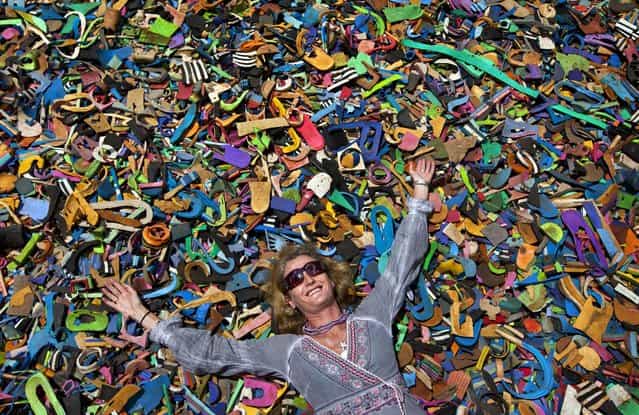 In this photo taken Monday, April 29, 2013, company owner and marine conservationist Julie Church poses for a photograph on a pile of pieces of discarded flip-flops used in a children's play area at the Ocean Sole flip-flop recycling company in Nairobi, Kenya. The company is cleaning the East African country's beaches of used, washed-up flip-flops and the dirty pieces of rubber that were once cruising the Indian Ocean's currents are now being turned into colorful handmade giraffes, elephants and other toy animals. (Photo by Ben Curtis/AP Photo)