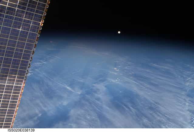 A full moon is visible with part of the International Space Station's solar array wing in this view above Earth's horizon, photographed by a crew member from the International Space Station while Space Shuttle Discovery (STS-128) remains docked with the station in this NASA handout photo taken September 3, 2009. (Photo by Reuters/NASA)