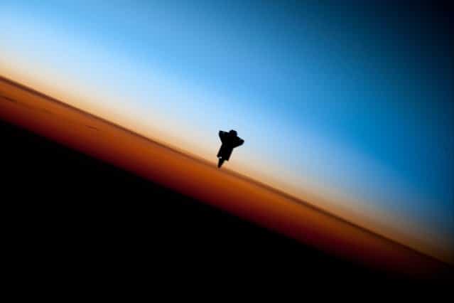 The space shuttle Endeavour is silhouetted against the backdrop of Earth's horizon prior to docking with the International Space Station in this picture taken by an Expedition 22 crew member on February 9, 2010 and released by NASA February 12, 2010. (Photo by NASA)