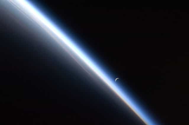 A full moon is visible with part of the International Space Station's solar array wing in this view above Earth's horizon, photographed by a crew member from the International Space Station while Space Shuttle Discovery (STS-128) remains docked with the station in this NASA handout photo taken September 3, 2009. (Photo by Reuters/NASA)
