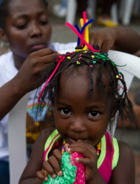 A girl gets an Afro-Colombian hairstyle during the 9th contest of Afro-hairdressers, in Cali, Valle del Cauca departament, Colombia, on May 12, 2013. The Afro hairstyles have their origins in the time of slavery, when women sat to comb their children hair after work. (Photo by Luis Robayo/AFP Photo)