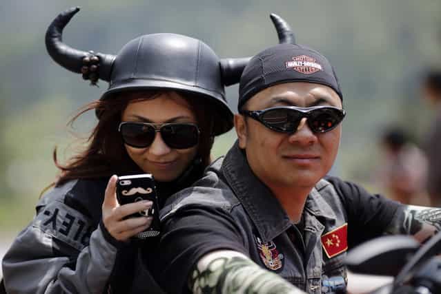 A couple rides a Harley Davidson motorcycle during the annual Harley Davidson National Rally in Qian Dao Lake, in Zhejiang Province, China, on May 11, 2013. Around 1,000 Harley Davidson enthusiasts from all over China met at the rally, as part of the company's 110-year anniversary. (Photo by Carlos Barria/Reuters)