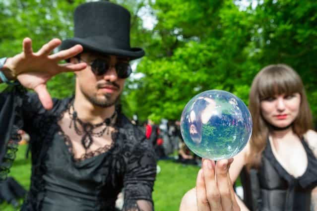 A man and a woman looking into a mirrorball attend the traditional park picnic on the first day of the annual Wave-Gotik Treffen, or Wave and Goth Festival, on May 17, 2013 in Leipzig, Germany. The four-day festival, in which elaborate fashion is a must, brings together over 20,000 Wave, Goth and steam punk enthusiasts from all over the world for concerts, readings, films, a Middle Ages market and workshops. (Photo by Marco Prosch)