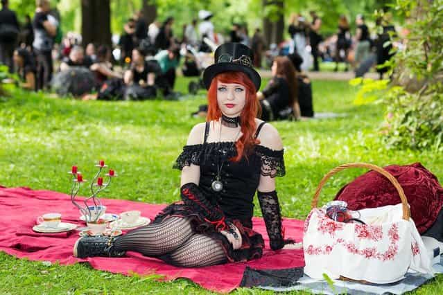 A girl sits on a red blanket on the lawn during the traditional park picnic on the first day of the annual Wave-Gotik Treffen, or Wave and Goth Festival, on May 17, 2013 in Leipzig, Germany. The four-day festival, in which elaborate fashion is a must, brings together over 20,000 Wave, Goth and steam punk enthusiasts from all over the world for concerts, readings, films, a Middle Ages market and workshops. (Photo by Marco Prosch)