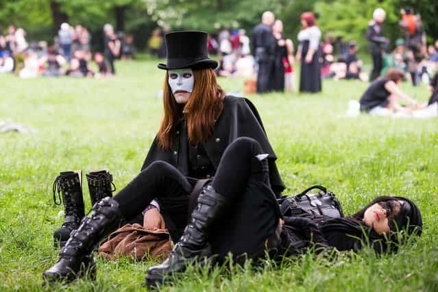A goth couple wearing masks rest on the lawn during the traditional park picnic on the first day of the annual Wave-Gotik Treffen, or Wave and Goth Festival, on May 17, 2013 in Leipzig, Germany. The four-day festival, in which elaborate fashion is a must, brings together over 20,000 Wave, Goth and steam punk enthusiasts from all over the world for concerts, readings, films, a Middle Ages market and workshops. (Photo by Marco Prosch)