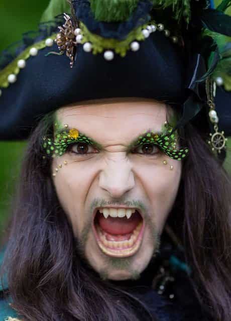 A man with fake vampire teeth wearing a pirate's costume attends the traditional park picnic on the first day of the annual Wave-Gotik Treffen, or Wave and Goth Festival, on May 17, 2013 in Leipzig, Germany. The four-day festival, in which elaborate fashion is a must, brings together over 20,000 Wave, Goth and steam punk enthusiasts from all over the world for concerts, readings, films, a Middle Ages market and workshops. (Photo by Marco Prosch)