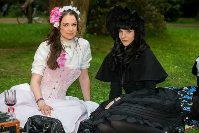 Two girls in black and white Victorian clothing pose for pictures during the traditional park picnic on the first day of the annual Wave-Gotik Treffen, or Wave and Goth Festival, on May 17, 2013 in Leipzig, Germany. The four-day festival, in which elaborate fashion is a must, brings together over 20,000 Wave, Goth and steam punk enthusiasts from all over the world for concerts, readings, films, a Middle Ages market and workshops. (Photo by Marco Prosch)