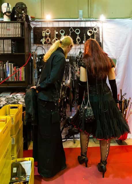 A couple looks at handcuffs and whips for sale at the Agra festival area on the first day of the annual Wave-Gotik Treffen, or Wave and Goth Festival, on May 17, 2013 in Leipzig, Germany. The four-day festival, in which elaborate fashion is a must, brings together over 20,000 Wave, Goth and steam punk enthusiasts from all over the world for concerts, readings, films, a Middle Ages market and workshops. (Photo by Marco Prosch)