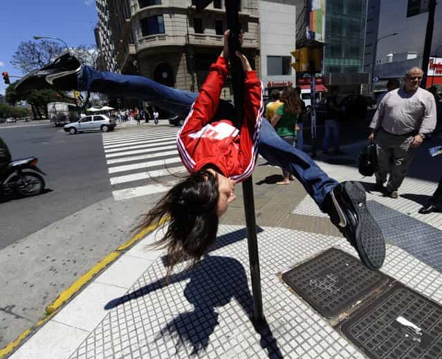 A Peruvian competitor of the Miss Pole Dance Sudamerica 2010, performs in front of the Obelisk, in downtown Buenos Aires on November 5, 2010, on the eve of the competition to be held in the city. The pole dance, born in night clubs in London, gradually grew and developed outside the field of sexuality and eroticism, as one of the most effective and fun activities when choosing a physical training routine. (Photo by Juan Mabromata/AFP Photo)