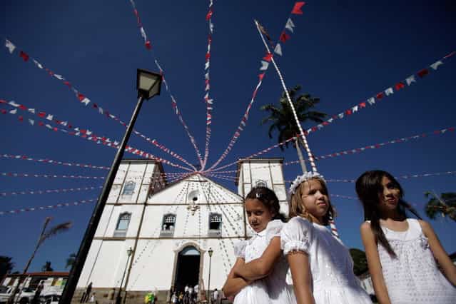 Girls representing angels stand in front of Our Lady of the Rosary church, during the [Cavalhadas] festival, in Pirenopolis, Brazil, Sunday, May 19, 2013. The popular festival is a tradition that was introduced in the 1800's by a Portuguese priest to mark the the ascension of Christ. The 3-day festival reenacts the Christian knights' defeat of the Moors. (Photo by Eraldo Peres/AP Photo)