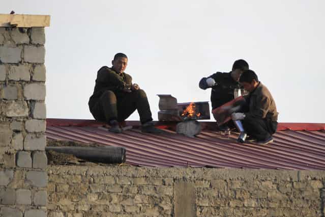 North Koreans work on the roof of a house along the banks of the Yalu River, near the North Korean town of Sinuiju, opposite the Chinese border city of Dandong, November 23, 2010. (Photo by Reuters/Stringer)