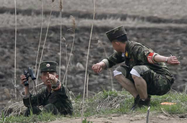 A North Korean soldier gestures toward a Chinese tourist boat after monitoring with a pair of binoculars on the bank of Hwanggumpyong island located in the middle of the Yalu River, near the North Korean town of Sinuiju and the Chinese border city of Dandong, April 30, 2012. (Photo by Jacky Chen/Reuters)
