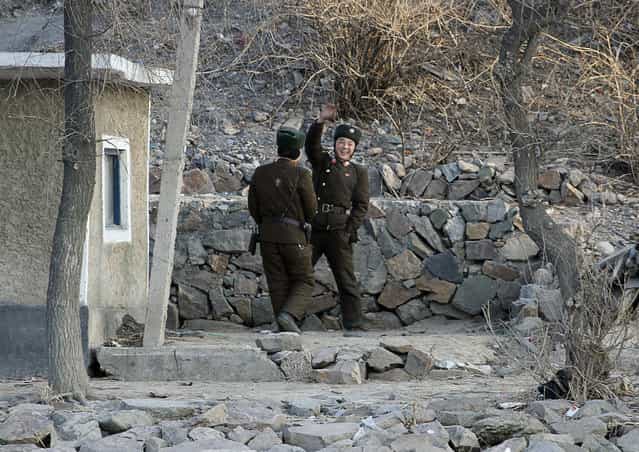 A North Korean soldier waves to a Chinese tourist boat on the banks of Yalu River near the North Korean town of Sinuiju, opposite the Chinese border city of Dandong, January 7, 2011. (Photo by Reuters/Stringer)