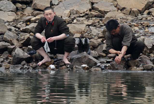 A North Korean soldier washes his socks as his comrade washes his hands at the banks of Yalu River, near the North Korean town of Sinuiju, opposite the Chinese border city of Dandong, April 8, 2013. (Photo by Jacky Chen/Reuters)