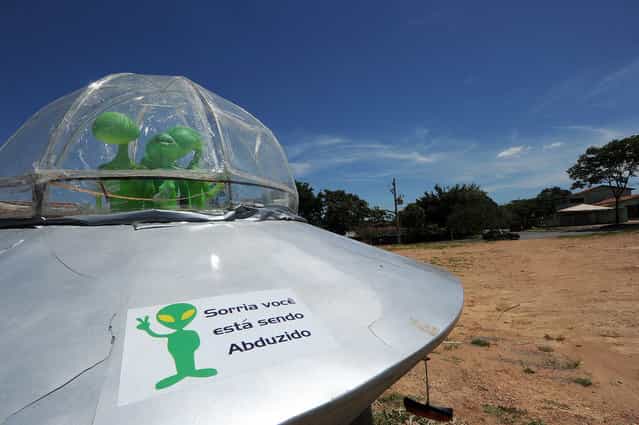 A mock UFO with alien dolls and reading [Smile, you are being abducted] is seen in Alto Paraiso town, Goias State, 230 kms north of Brasilia, on December 20, 2012. Situated over a huge quartz crystal plate, Alto Paraiso attracted many Brazilians and foreigners seeking refuge from the events expected by the Mayan prophecy that predicts the end of the world or the beginning of a new era. (Photo by Evaristo Sa/AFP Photo)