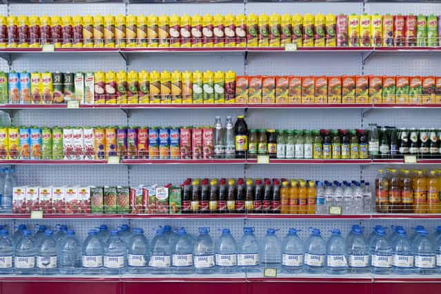 Precisely stacked drinks in a store in the center of Ashgabat. The main street of the capital features lavish shops which were part of the architectural grand plan but are seldom used by locals. Daily life under the new president is reportedly easier than before when food shortages were common. [We might not always be able to afford it, but the food is there] said one student. (Photo by Amos Chapple via The Atlantic)