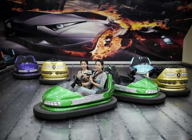 Two young women strap themselves into bumper cars in the Alem Entertainment Center. (Photo by Amos Chapple via The Atlantic)