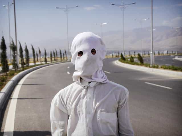 A gardener shrouded against the sun on a 104F (40C) day in Ashgabat. Despite their country's wealth, ordinary people receive little economic trickle-down. Workers like this one earn around $150 a month maintaining the white marble city. (Photo by Amos Chapple via The Atlantic)