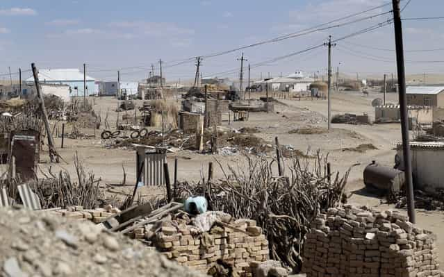 120 miles from the opulence of Ashgabat is the village of Erbent. In 2004 President Niyazov commented on the ugly appearance of the nearby village of Derweze. Three weeks later the residents were evicted and the village razed to the ground. Many of the displaced now live in yurts here in Erbent. The site of Derweze today is a discolored smudge on the desert floor. (Photo by Amos Chapple via The Atlantic)