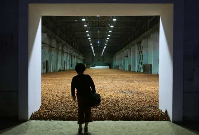 A Chinese visitor views a massive sculptural installation filling a factory warehouse at an exhibition by British artist Antony Gormley called [Asian Field] in Shanghai October 7, 2003. [Asian Field] is comprised of 192,000 clay figures, made under the guidance of Gormley, by over 300 people of all ages in China's Guangdong province using more than 100 tons of clay. (Photo by Claro Cortes IV/Reuters)