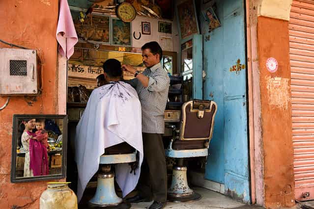 [At the barber shop]. A woman holding her baby is waiting the husband at the barber shop. Location: Jaipur, Rajasthan, India. (Photo and caption by Massimiliano De Santis/National Geographic Traveler Photo Contest)