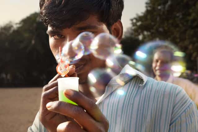 [Bubbles]. A man blowing bubbles on the beach shares a moment, allowing me a couple seconds to play with the composition of the pedestrians behind him. Location: Mumbai, India. (Photo and caption by Chris Mumma/National Geographic Traveler Photo Contest)