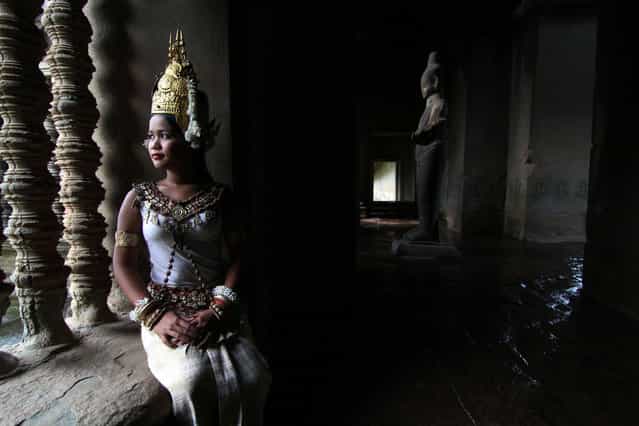 [Apsara dancer in deep thought]. This Apsara dancer was in deep thought. She was seated inside the Angkor Wat temple in Siem Reap with a statue in shadow and water dripping past on the ground. Location: Siem Reap, Cambodia. (Photo and caption by Bonnie Stewart/National Geographic Traveler Photo Contest)