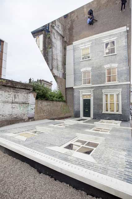 A large-scale installation art piece by Leandro Erlich, named [Dalston House], is displayed on June 24, 2013 in London, England. Part of the [Beyond Barbican] summer series of events, the interactive installation is a full facade of a late nineteenth-century Victorian terraced house built on the ground with a large mirror above it to reflect people as to appear dangling from the structure. (Photo by Dan Dennison/Getty Images)