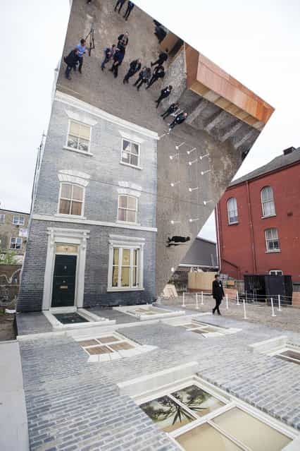 A large-scale installation art piece by Leandro Erlich, named [Dalston House], is displayed on June 24, 2013 in London, England. Part of the [Beyond Barbican] summer series of events, the interactive installation is a full facade of a late nineteenth-century Victorian terraced house built on the ground with a large mirror above it to reflect people as to appear dangling from the structure. (Photo by Dan Dennison/Getty Images)