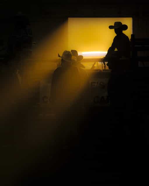 [Cowboy in a ribbon of light]. Rodeos always provide a sense of place. There's action, dirt, pride, you name it. It's a loud, flashy sport, with cheering and showboating. But on the underbelly are quiet moments. The moments between bucking broncs, beer drinking and the announcers crude jokes. Moments like this one, where a young boy waits patiently for the next horse to come charging out of the chutes. Location: Helena, Montana. (Photo and caption by Dylan Brown/National Geographic Traveler Photo Contest)