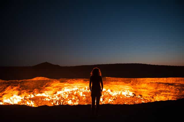 [Door to Hell]. Standing at the edge of the Darvaza Crater in Turkmenistan. Known as the Door to Hell, this flaming crater has been burning for decades, fueled by the rich natural gas reserves found below the surface. Location: Darvaza, Turkmenistan. (Photo and caption by Priscilla Locke/National Geographic Traveler Photo Contest)