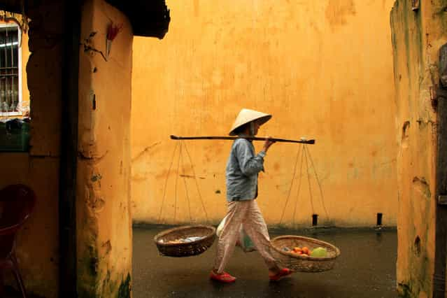 [Sellers of Vietnam]. Seen here is a typical hawker in Vietnam. She sells fruits and other eatables mostly. Spotted her in the ancient port town of Hoi An in Central Vietnam. Such hawkers are a common sight in the country. Getting her against a yellow old wall was indeed a precious frame to carry home. (Photo and caption by Shynil Hashim/National Geographic Traveler Photo Contest)