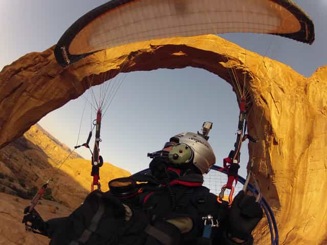 [Flying Through the Arch]. A paramotor pilot flies through the Corona Arch near Moab, Utah. This daring feat was captured with a GOPRO Hero 2 camera and made possible by the incredible flying machine called the Paramotor. (Photo and caption by Glenn Tupper/National Geographic Traveler Photo Contest)