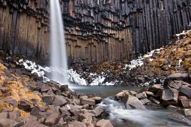[Svartifoss (The Black Fall)]. Svartifoss (The Black Fall) is surrounded by dark lava columns, which give rise to its name. The hexagonal columns were formed inside a lava flow which cooled extremely slowly, giving rise to crystallization. Location: Skaftafell National Park, Iceland. (Photo and caption by Giacomo Ciangottini/National Geographic Traveler Photo Contest)