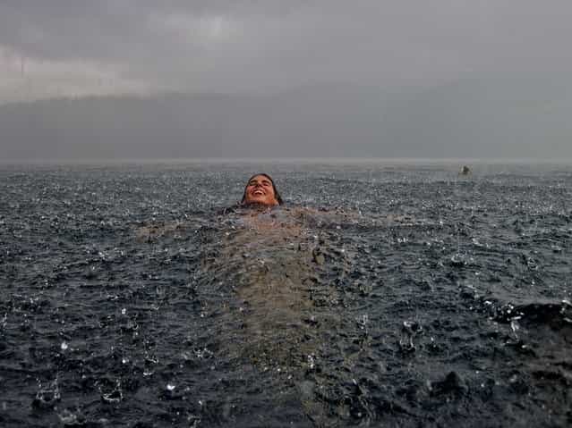 [Merit Winner: Swimming in the Rain]. My sister in the south of Chile. We are sitting at home next to the fireplace in our southern lake house when it suddenly began to pour uncontrollably. Had to rush into the lake to take this snapshot! Location: Lago Caburgua, Chile. (Photo and caption by Camila Massu/National Geographic Traveler Photo Contest)