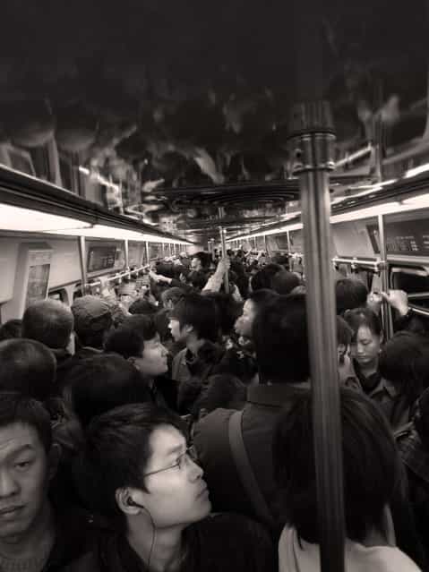 [People People People and more People]. Here's a typical guy who's trying to tune out all the people in the Beijing Subway. It feels like all 1.2 billion people is trying to fit this cart. (Photo and caption by Brian Yen/National Geographic Traveler Photo Contest)