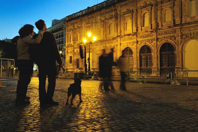 [Enjoing Seville]. A couple with their pet watching the baroque style facade of the City Town Hall in Plaza San Francisco at Seville, Spain. It was twilight of a January day yet the fantastic climate of Andalucia welcomed people to take a walk just wearing a sweater. (Photo and caption by Stefano Spezi/National Geographic Traveler Photo Contest)