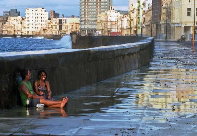 [Fun on the Malecon]. While strolling down the Malecon in Havana, Cuba, I came across this couple. They were laughing and drinking and getting soaked by an occasional wave that broke over the sea wall. They were oblivious to the rest of the world while they enjoyed each other immensely. (Photo and caption by Jim Tardio/National Geographic Traveler Photo Contest)