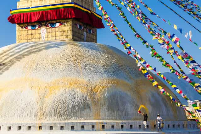 [Cleaning The Stupa]. Custodians fling yellow colored water made from saffron onto Bodhnath Stupa in Nepal. The yellow arc represents the double lotus. Bodhnath Stupa, located in the Kathmandu Valley, lies on the ancient trade route from Tibet and attracts thousands of pilgrims and tourists daily. (Photo and caption by Craig Ferguson/National Geographic Traveler Photo Contest)
