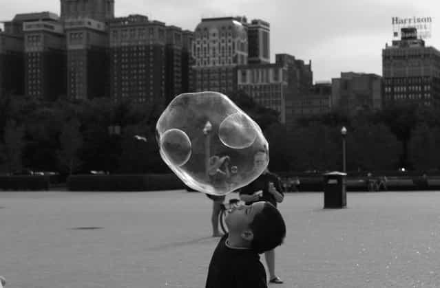 [Double, No, Triple Bubble]. While biking in the city of Chicago my significant other and I stopped to watch a street performer create giant bubbles. The bubbles were attracting adults and kids alike. I nearly got trampled by the wild children chasing the floating soap. I caught a few myself as well as some decent shots. (Photo and caption by Sarah Yost/National Geographic Traveler Photo Contest)