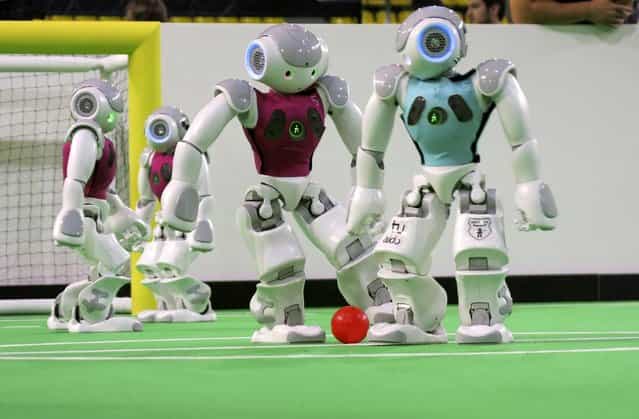 In this photo taken Thursday, June 27, 2013 robots in the [standard platform] division compete at the RoboCup championships in Eindhoven, Netherlands. Around 300 teams from 40 countries are competing this week in the RoboCup championships. The competition has the long-term goal of building a team of androids good enough to beat the human world cup team by 2050. (Photo by Toby Sterling/AP Photo)